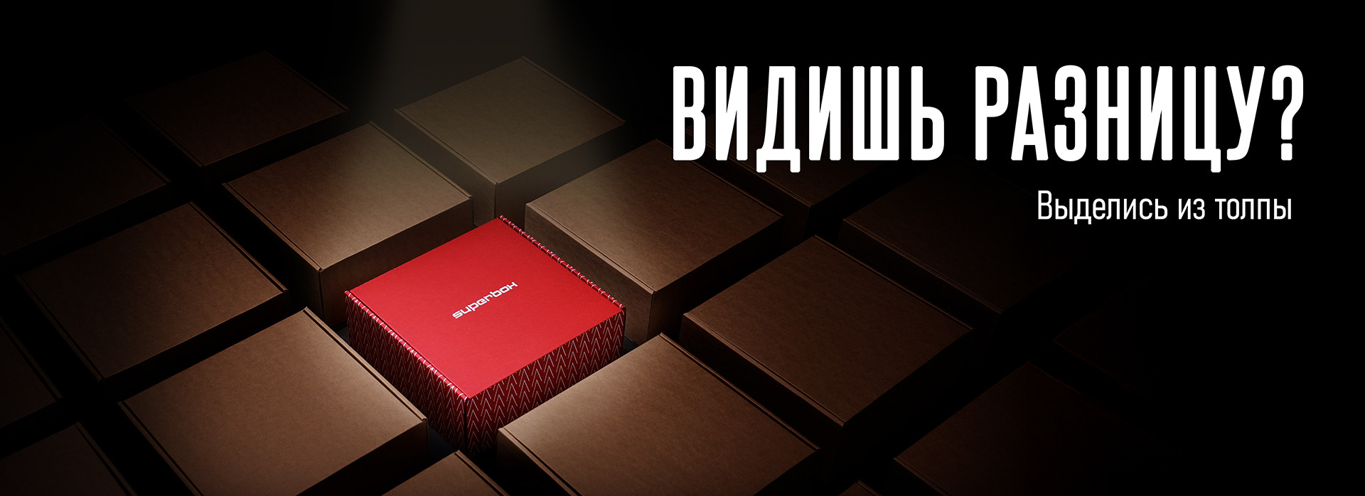 Ярко-красная коробка выделяется среди тусклых коричневых коробок, с текстом «Видишь разницу?» в свете прожектора